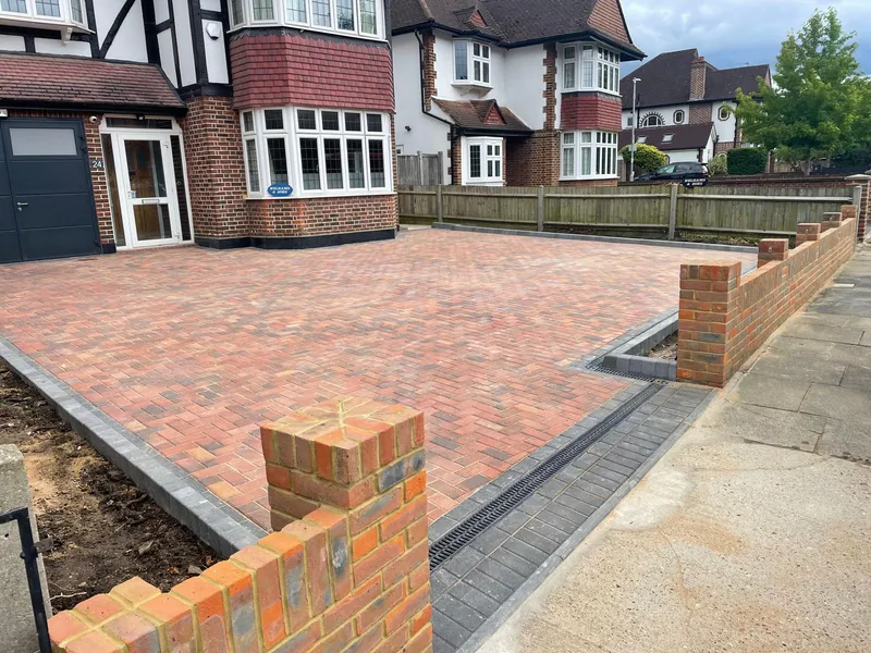 Finished block paved driveway in Epsom with a herringbone pattern and brick boundary wall